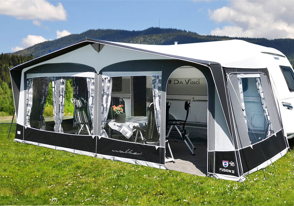 Angled exterior view of Walker Fusion 2 Caravan Awning attached to a white caravan on a grassy campsite with mountain background.