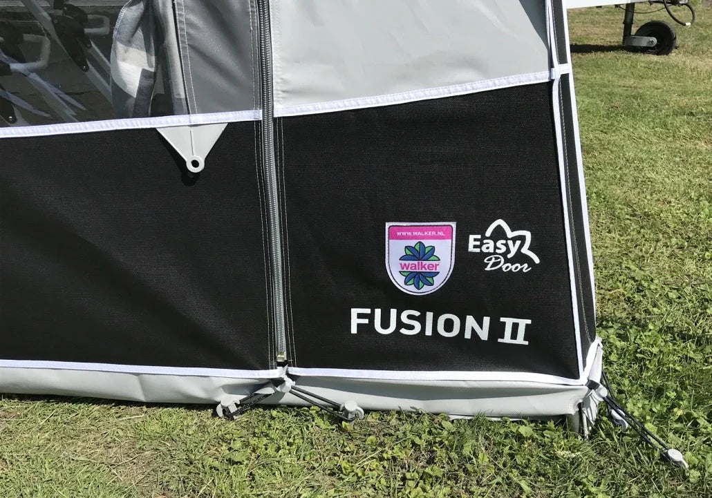 Close-up of Walker Fusion 2 Caravan Awning Easy Door branding and lower front panel detail on a grassy campsite background.