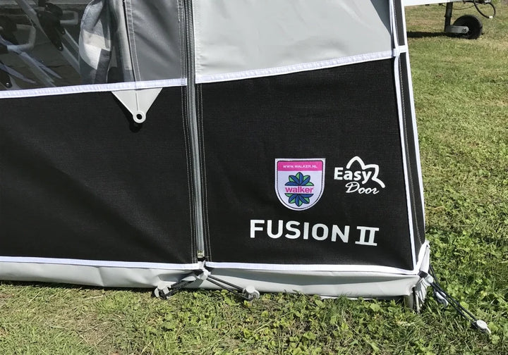 Close-up of Walker Fusion 2 Caravan Awning Easy Door branding and lower front panel detail on a grassy campsite background.