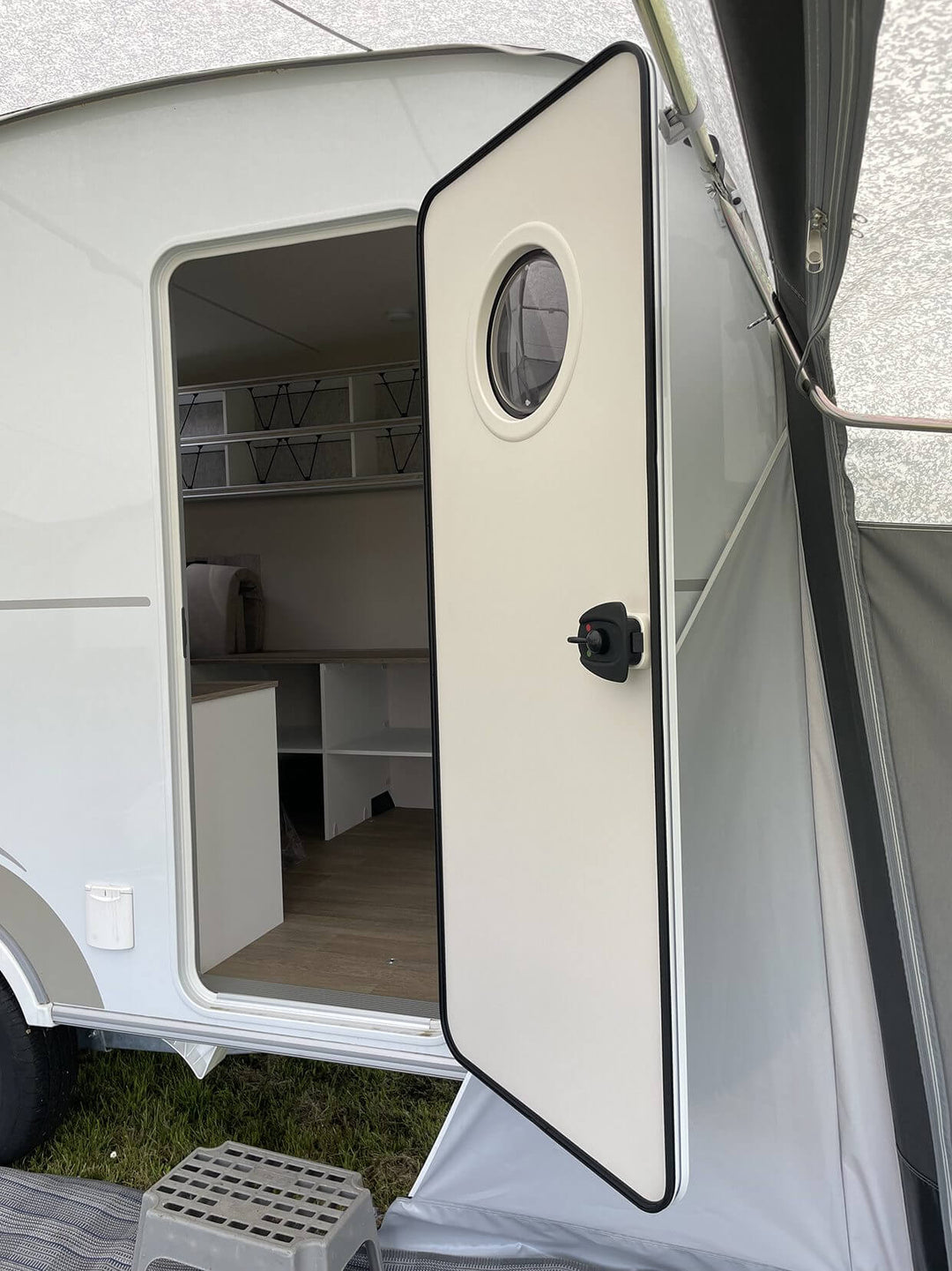 Beachy caravan door open into Walker awning, showing tidy interior and small entry step.