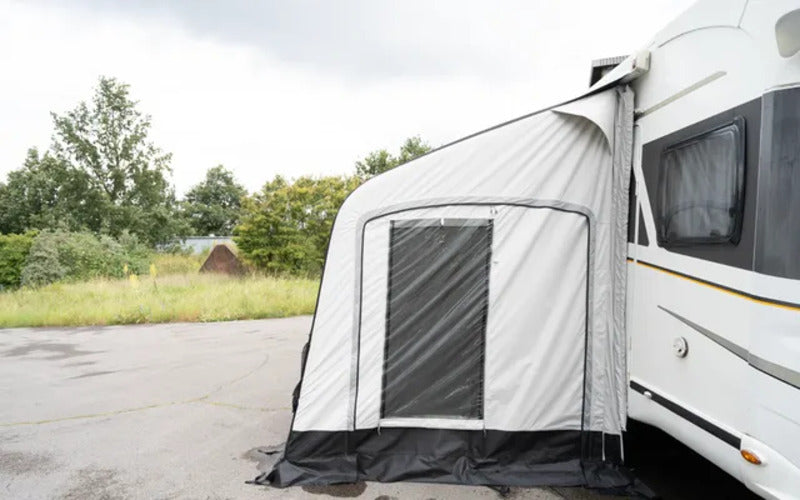 Side view of the Westfield Vega 200 air awning connected to a motorhome on a paved campsite.