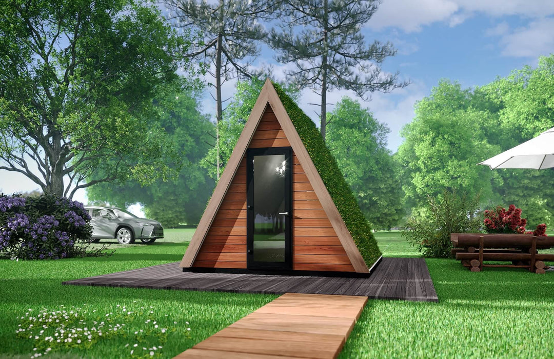 Frontal view of green-roofed glamping pod with wooden path leading to the door, surrounded by lush landscape and trees.